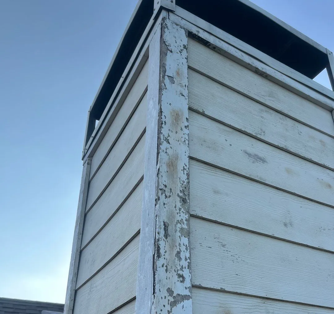 Image of a chimney siding in need of repair and being inspected by MD roofing and construction